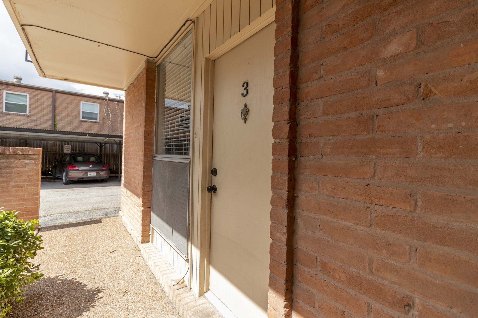 Unit entry with mid-century brick framing and the original door knocker.