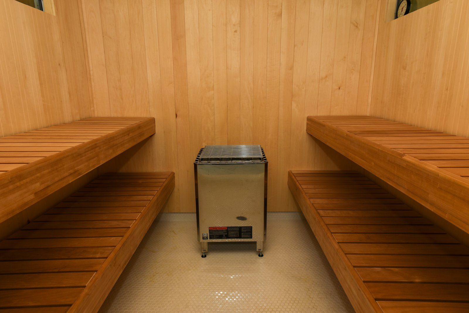 Inside the Nordic sauna: cedar walls and benches around the stainless heater.